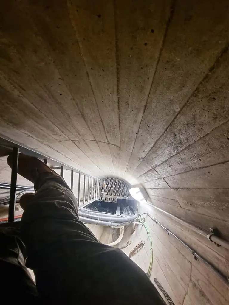 Crew member from Fidato climbing a ladder inside a water tower